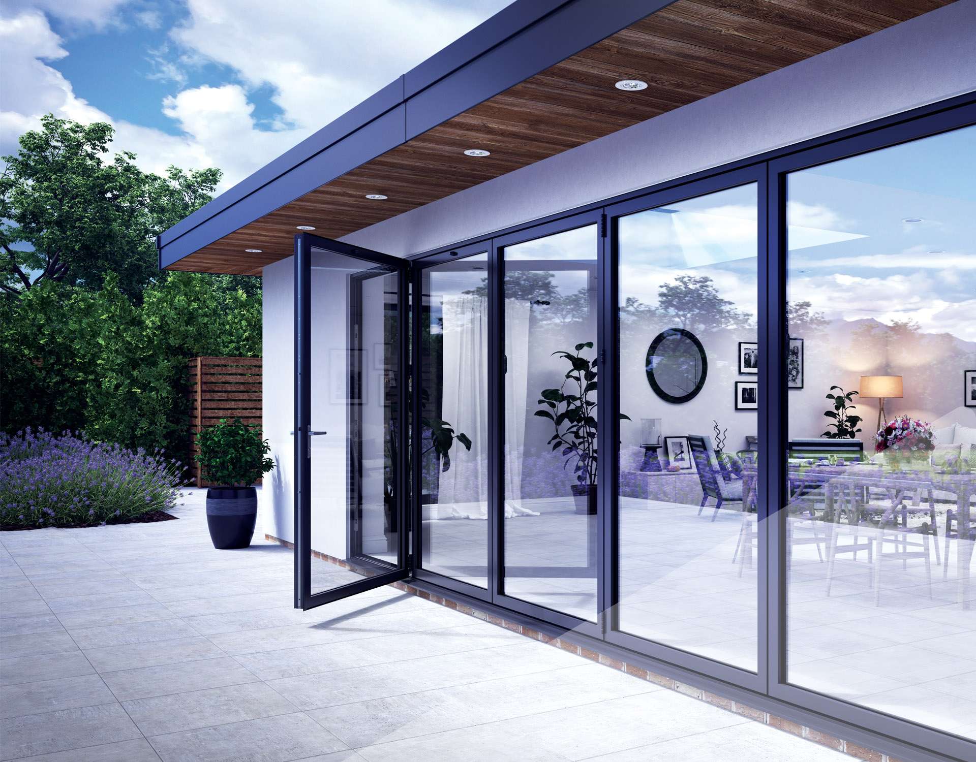External shot of a white extension with Korniche bi-folding doors installed. The traffic door is pen and the sky is reflecting off the glass.In the far left of the image green trees cane seen below a bright blue sky and clouds.