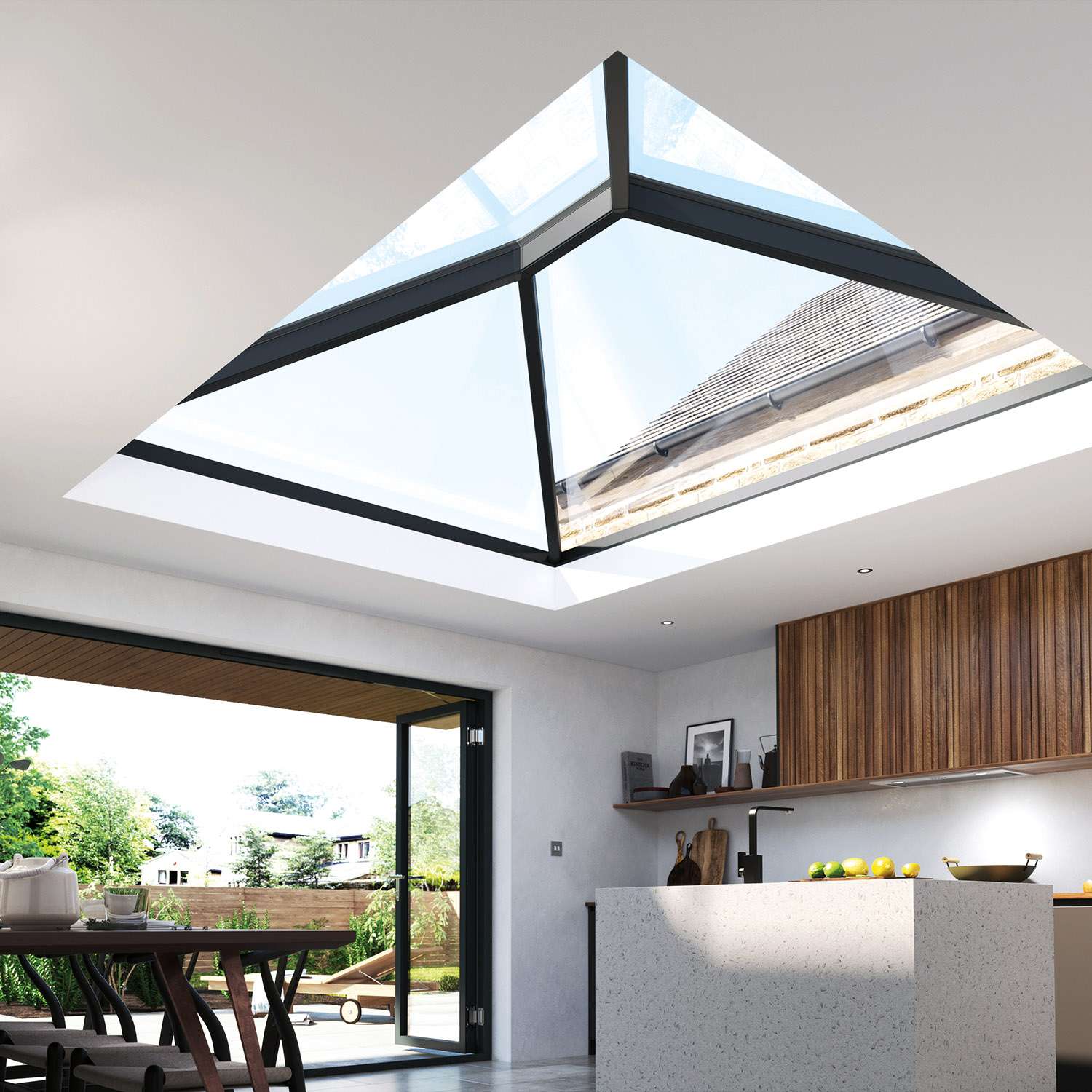 A modern kitchen with a large roof Korniche roof lantern installed in the roof. Bifold doors open out into a garden, where a deckchair is situated on the pavement.